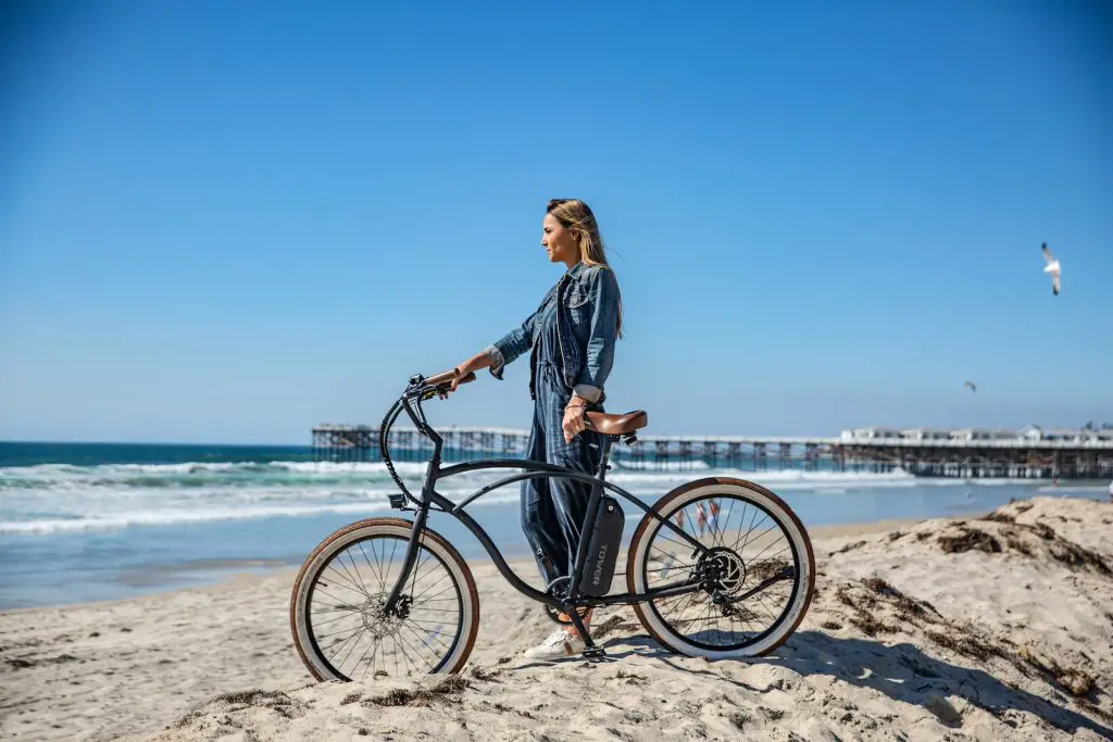 woman standing beside black cruiser bike on seashore during daytime